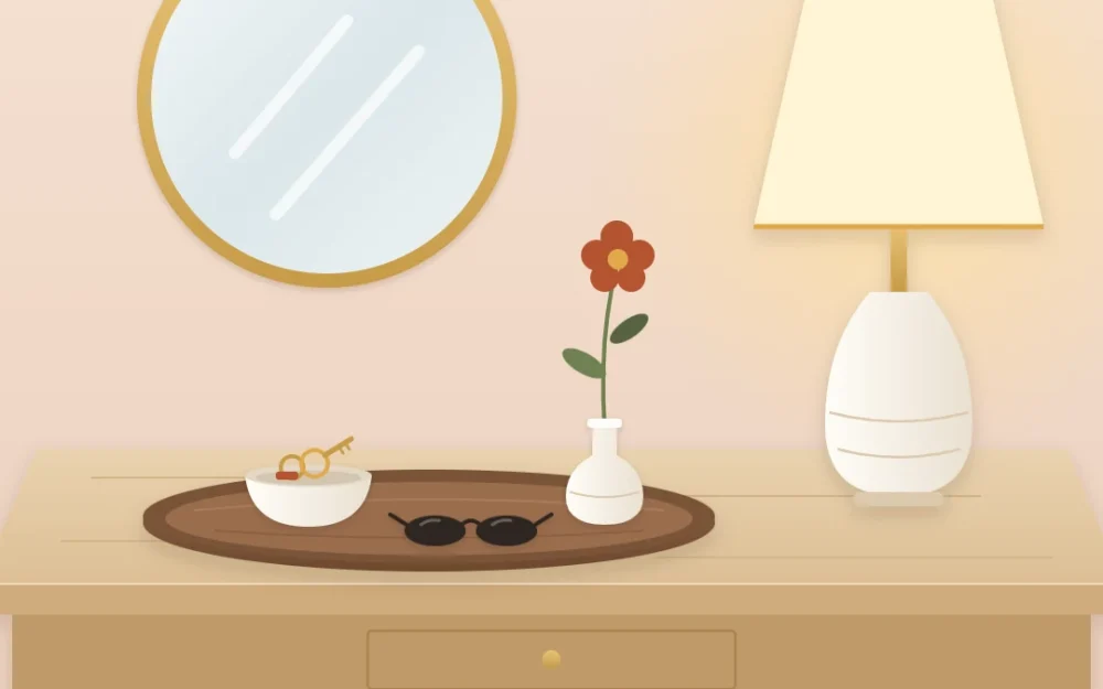 Console surface with an oval wooden tray holding a ceramic bowl with keys, sunglasses and a bud vase, beside a lamp base